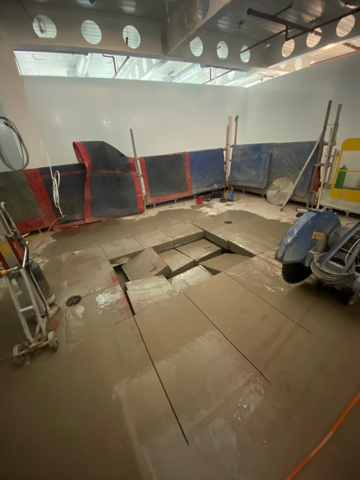 Commercial floor slab saw-cut into sections and lifted for removal.